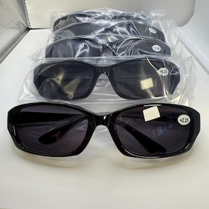 May include: Four pairs of black sunglasses with dark lenses, each in a clear plastic package. The sunglasses have a +2.25 magnification. The frames are a glossy black, and the lenses are dark, providing sun protection.