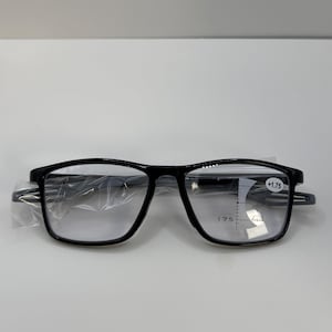 May include: Black rectangular eyeglasses with clear lenses. The glasses have a +1.75 magnification and are in a plastic sleeve. The frames are a glossy black color.