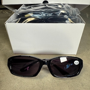 May include: Black reading glasses with a +2.25 magnification, displayed in a white box. The glasses have a rectangular frame and dark lenses. Several pairs are visible in the box, suggesting a bulk purchase.