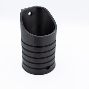 Puede incluir: Soporte para teléfono impreso en 3D de plástico negro con un diseño acanalado. El soporte tiene una parte superior redondeada y una parte inferior plana.