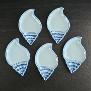 May include: Set of five white ceramic dishes shaped like seashells with blue and white painted designs.