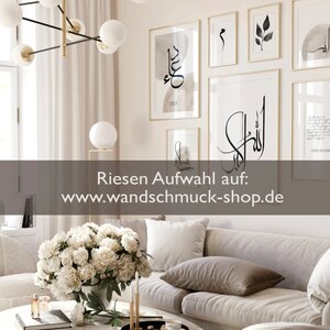 Peut inclure: Un int&eacute;rieur de salon avec un canap&eacute; gris et des fleurs blanches dans un vase sur une table basse. Le mur est d&eacute;cor&eacute; d'impressions d'art de calligraphie noir et blanc encadr&eacute;es. Le texte sur le mur indique "DUA" et "ALLAH". Le texte en bas de l'image indique "Riesen Auswahl auf: www.wandschmuck-shop.de".