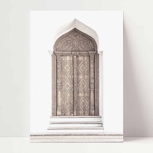 May include: A large, intricately carved wooden door with a pointed archway. The door is made of dark wood and has a detailed pattern of geometric shapes and floral designs. The door is set against a white background.