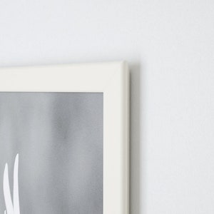Peut inclure: Un cadre photo blanc avec une image grise et blanche &agrave; l'int&eacute;rieur. Le cadre est sur un mur blanc.