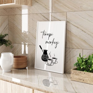 Peut inclure: Une impression encadr&eacute;e blanche avec du texte noir qui dit "Terapi merkezi" et une illustration en noir et blanc d'une cafeti&egrave;re et de deux tasses de caf&eacute;.