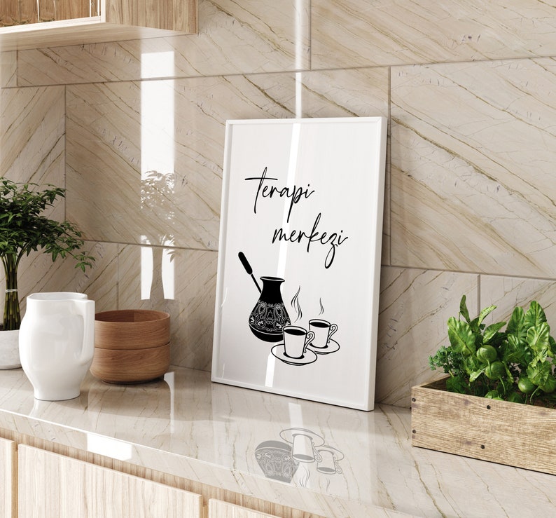 Peut inclure: Une impression encadr&eacute;e blanche avec du texte noir qui dit "Terapi merkezi" et une illustration en noir et blanc d'une cafeti&egrave;re et de deux tasses de caf&eacute;.