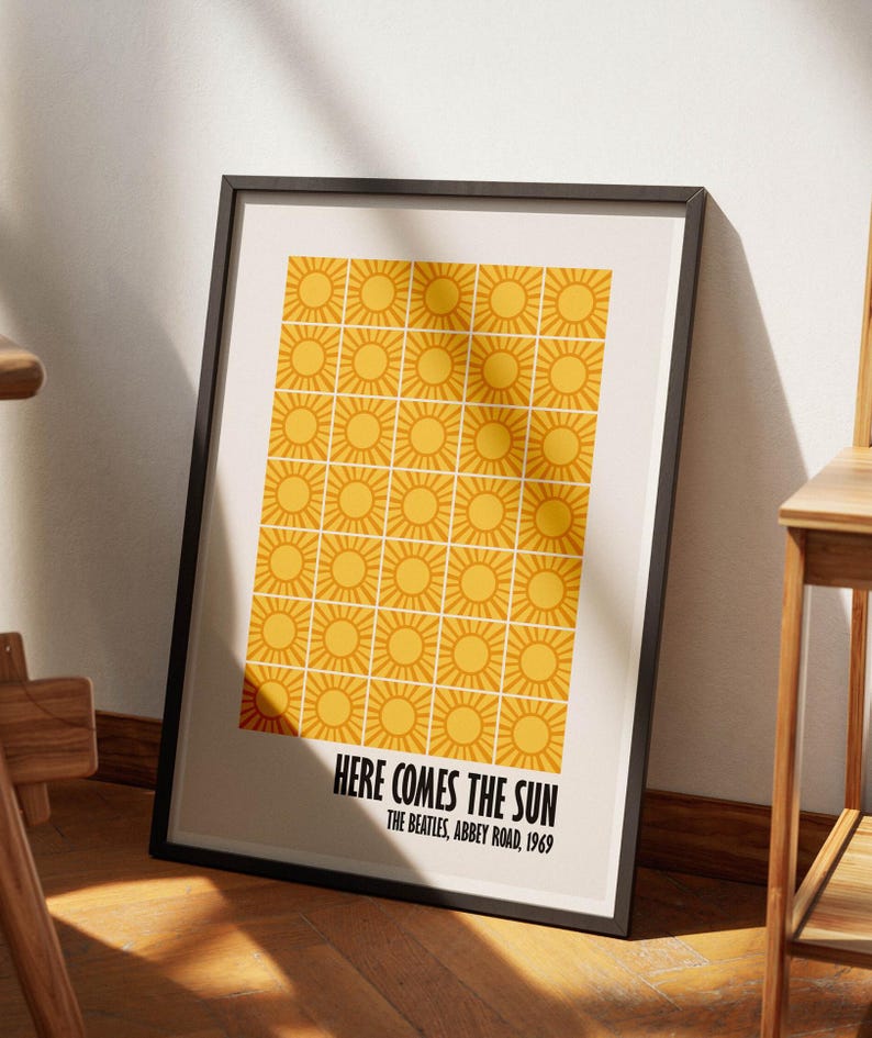 Peut inclure: Impression d'art encadr&eacute;e avec un motif r&eacute;p&eacute;t&eacute; de soleils jaunes sur fond cr&egrave;me. Le texte "HERE COMES THE SUN" et "THE BEATLES, ABBEY ROAD, 1969" sont imprim&eacute;s en noir en bas. Le cadre est noir.