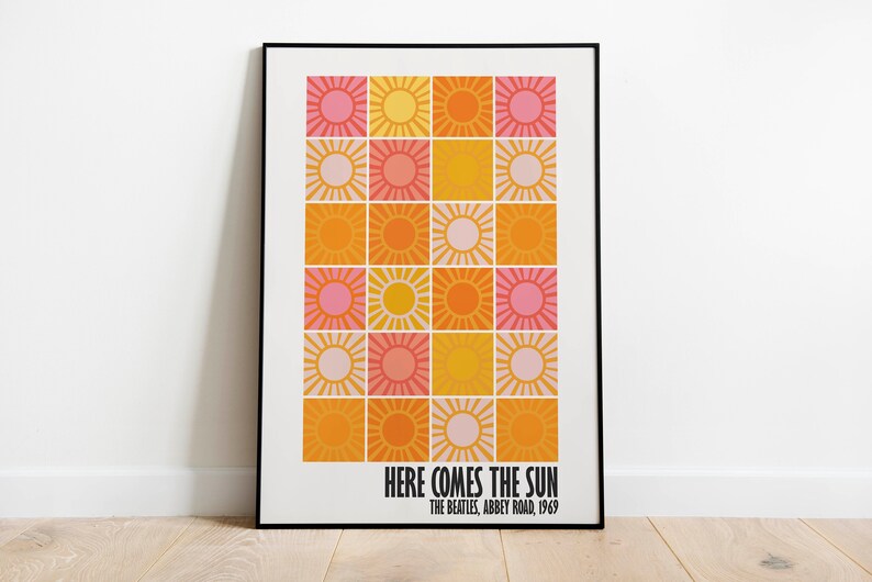 Peut inclure: Une affiche encadr&eacute;e avec une grille d'illustrations de soleil aux couleurs rose, orange et jaune. Le texte "HERE COMES THE SUN" est affich&eacute; en dessous, avec "THE BEATLES, ABBEY ROAD, 1969".