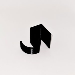 May include: A black, abstract hook-shaped object. The hook has a curved lower section and a right-angled upper section. The object is set against a plain white background, highlighting its form and design.