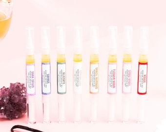 Puede incluir: Ocho tubos transparentes con tapas blancas que contienen aceite para cutículas perfumado. Los tubos están etiquetados con diferentes aromas, incluyendo "Rouge", "Snow Angel", "Flower Boom", "Brazil BumBum", "Seychelles", "Alienate", "Savage" y "Dark Opium".
