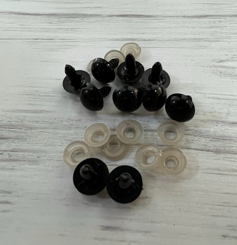 Puede incluir: Un conjunto de ojos de seguridad de pl&aacute;stico negro con arandelas de pl&aacute;stico transparente. Los ojos tienen un aspecto brillante y redondeado, dise&ntilde;ados para manualidades y fabricaci&oacute;n de juguetes. Las arandelas son planas y circulares.