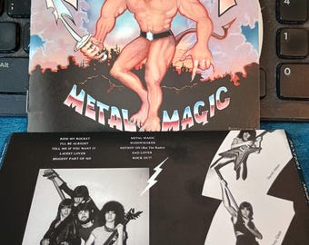May include: A Pantera "Metal Magic" album cover featuring a muscular, anthropomorphic cat-like figure holding a sword. The album art is set against a blue sky background. The back of the album features band photos and a tracklist.
