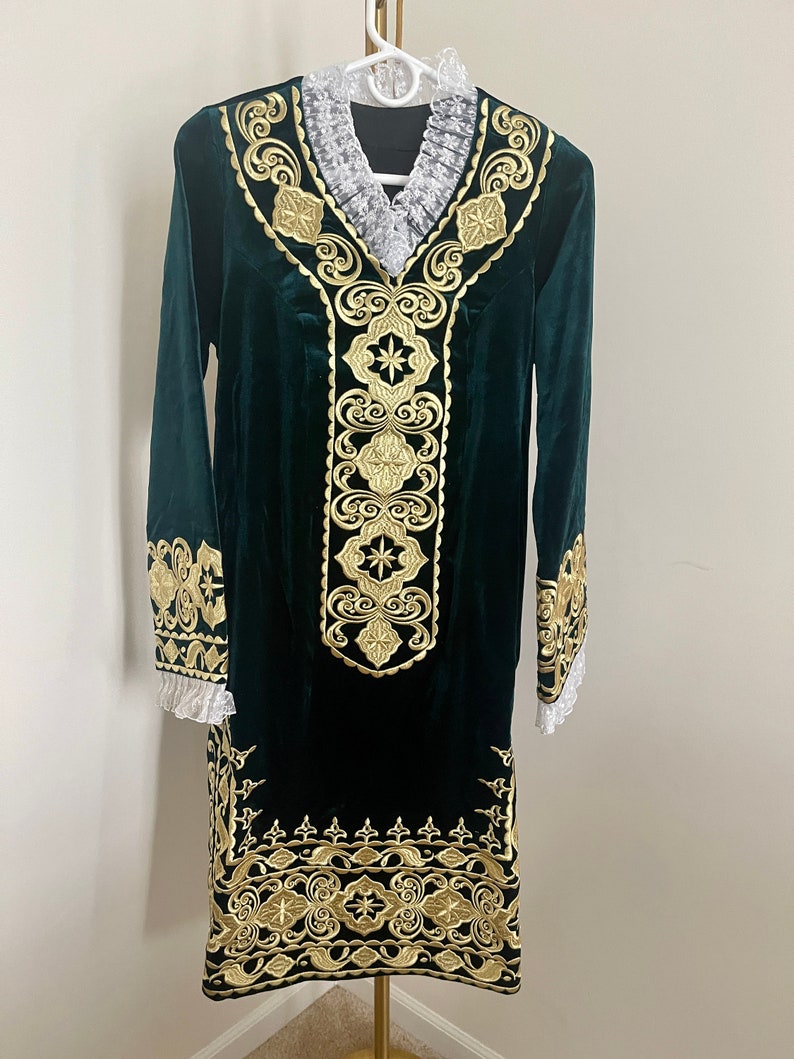 May include: A long-sleeved green velvet dress with gold embroidery. The dress has a V-neckline and a lace trim around the neckline and sleeves.