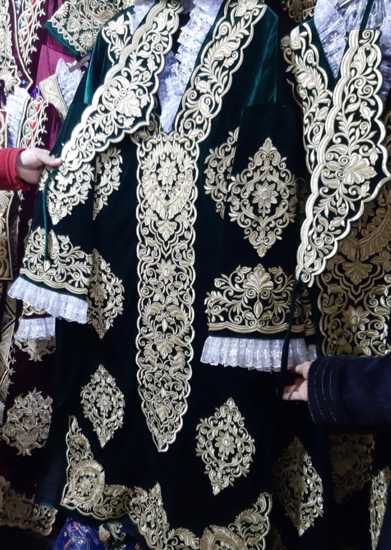May include: A dark green velvet garment with intricate gold embroidery. The garment features a floral design and a lace trim.