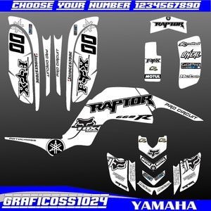 Op de afbeelding: Witte Yamaha Raptor 660R ATV-graphics kit met zwarte en witte Fox Racing, Bridgestone, GoPro, Motul en Dineal-logo's. De kit bevat een nummerplaat met het nummer 00, een voorspatbord-graphic en een achterspatbord-graphic.