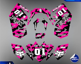 May include: Pink and black motocross graphic kit with a camouflage pattern. The kit includes a number plate with the number "01" and the word "Suzuki" on it. The kit also includes a Fox Racing logo and the words "Dunlop" and "Protaper".
