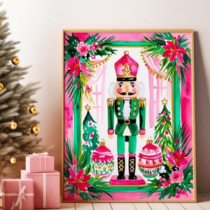 May include: A framed watercolor print of a Christmas nutcracker soldier in a green uniform and pink hat, surrounded by festive decorations. A silver Christmas tree with gold ornaments and pink wrapped gifts are in the foreground.