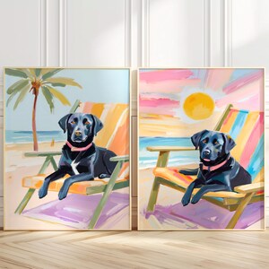 May include: Two black Labrador Retrievers are sitting in beach chairs on a beach. The chairs are colorful and have striped fabric. The dogs are wearing pink collars. The background is a colorful sunset with a bright yellow sun.