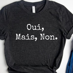 May include: A dark gray t-shirt with the text "Oui, Mais, Non." printed in white.