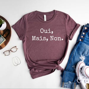 May include: A maroon t-shirt with the text "Oui, Mais, Non." printed in white.