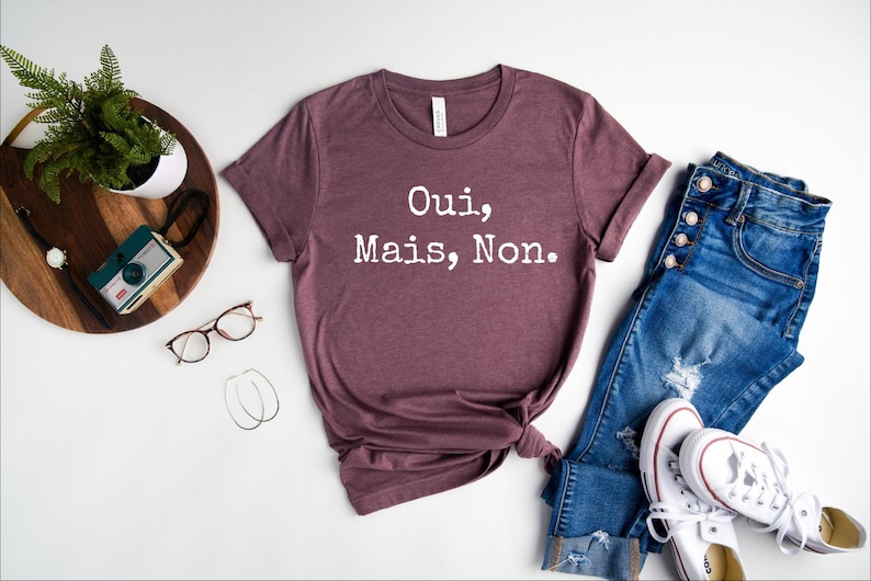 May include: A maroon t-shirt with the text "Oui, Mais, Non." printed in white.