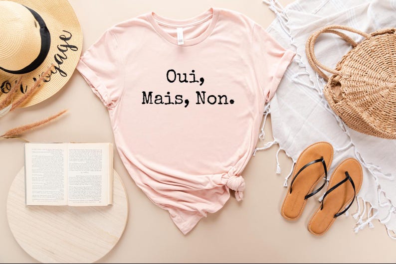 May include: A pink t-shirt with the text "Oui, Mais, Non." printed in black.