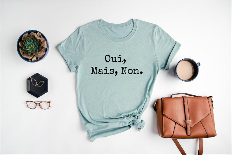 May include: A light blue t-shirt with the text "Oui, Mais, Non." printed in black.