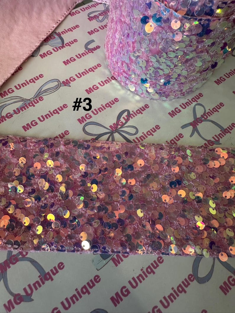 Op de afbeelding: Roze paillettenlint en stof met iriserende pailletten. De afbeelding toont een rol lint en een stuk stof, beide bedekt met glinsterende pailletten. De tekst "#3" is zichtbaar op de achtergrond.