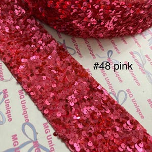 Op de afbeelding: Een rol roze paillettenlint. Het lint is bedekt met kleine, ronde, glanzende pailletten. De tekst "#48 pink" is zichtbaar op de verpakking. Het lint wordt waarschijnlijk gebruikt voor knutselen, naaien of versieren.