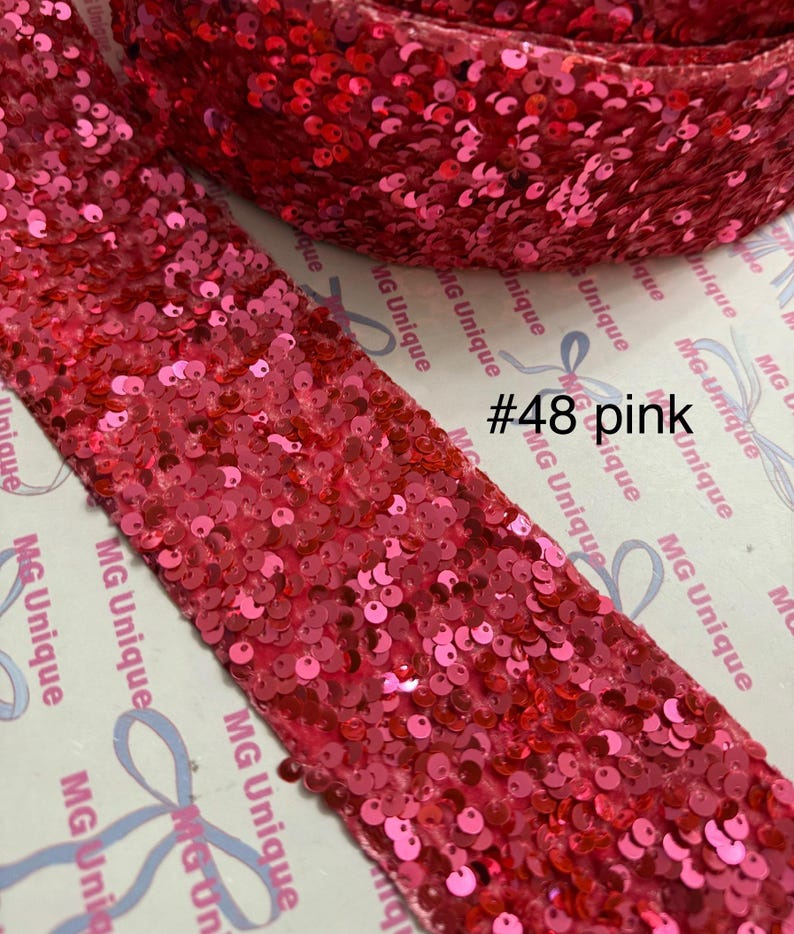 Op de afbeelding: Een rol roze paillettenlint. Het lint is bedekt met kleine, ronde, glanzende pailletten. De tekst "#48 pink" is zichtbaar op de verpakking. Het lint wordt waarschijnlijk gebruikt voor knutselen, naaien of versieren.