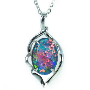 Puede incluir: Un collar de cadena de plata con un colgante que presenta una gran piedra de ópalo de forma ovalada con un brillo iridiscente negro, azul, verde y rosa. El ópalo está engastado en un diseño de espiral de plata.