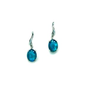 May include: A pair of silver dangle earrings with oval-shaped blue gemstones.