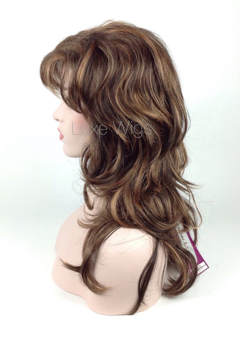 May include: A long, wavy brown wig with blonde highlights. The wig is styled in a layered, casual look.
