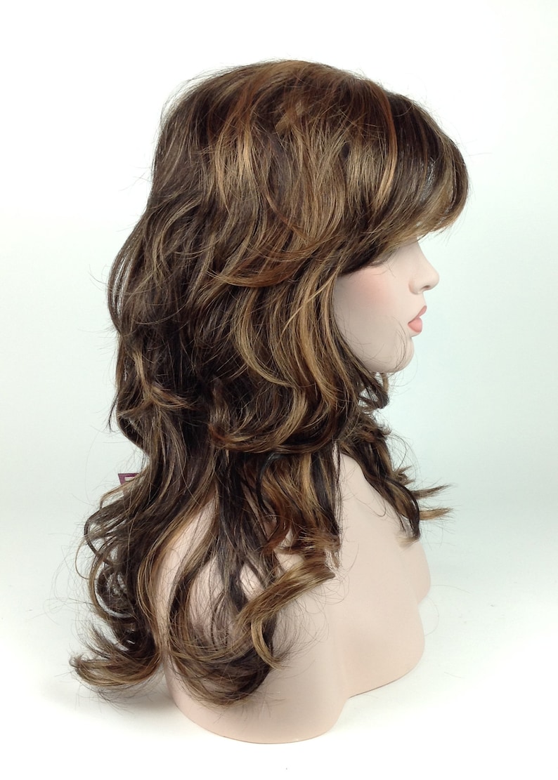 May include: A long, wavy brown wig with blonde highlights. The wig is styled with layers and a side parting.