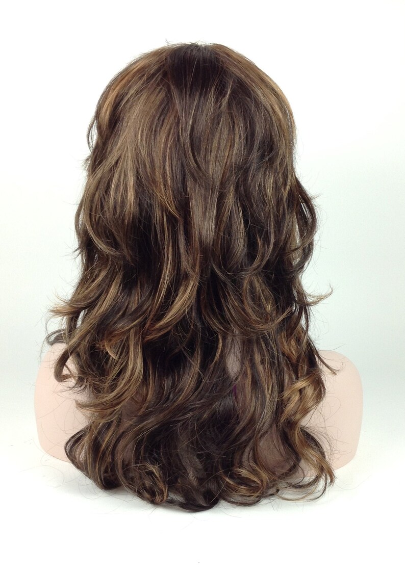 May include: A long, wavy brown wig with blonde highlights. The wig is styled in loose curls and falls to the shoulders.
