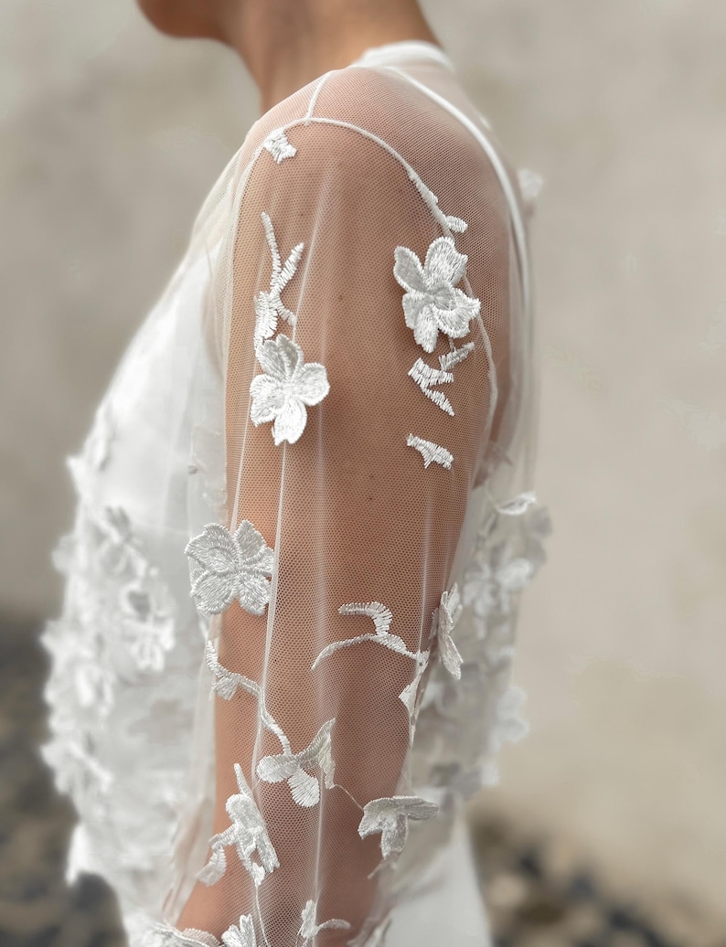 May include: White sheer lace overlay with floral embroidery. The lace has a delicate floral pattern with small white flowers.