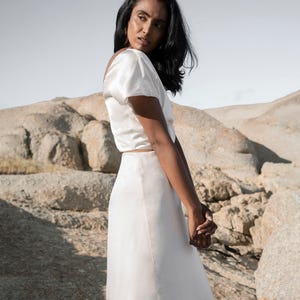 May include: A white satin top with short sleeves and a white satin skirt.