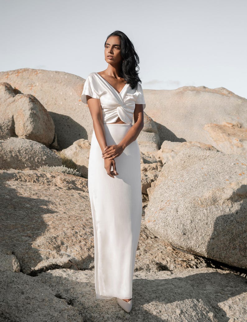 May include: A white satin top with a twist detail at the front and a white satin maxi skirt.