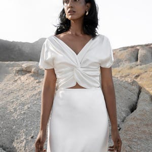 May include: A white satin top with a twist detail at the front and a matching white satin skirt.