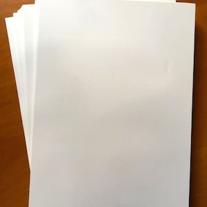 Puede incluir: Una pila de hojas de papel blanco sobre una superficie de madera.