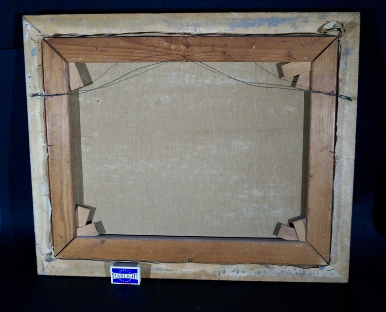 May include: The back of a wooden picture frame with a canvas stretched inside. The frame is made of dark wood and has a simple design. The canvas is a light brown color and is attached to the frame with staples. There is a small, blue and white matchbook on the bottom of the frame that says "Starlight".