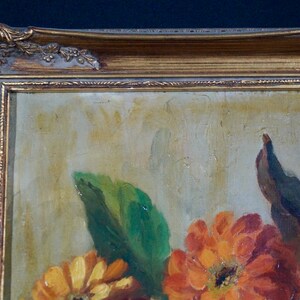 May include: A framed oil painting of a still life featuring a bouquet of orange, red, and yellow flowers with green leaves. The painting is in a gold frame with ornate details.