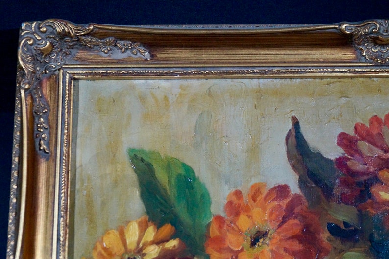 May include: A framed oil painting of a still life featuring a bouquet of orange, red, and yellow flowers with green leaves. The painting is in a gold frame with ornate details.