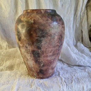 Könnte beinhalten: Eine braune Keramikvase mit einer marmorierten, strukturierten Oberfläche. Die Vase hat einen abgerundeten Boden und eine leicht ausgestellte Öffnung.