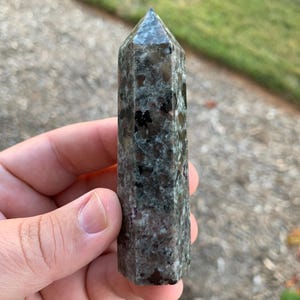 May include: A green, black, and pink crystal point with a pointed tip. The crystal is smooth and polished.