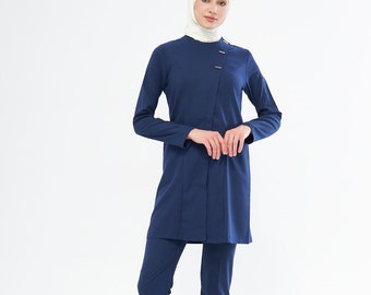 May include: A navy blue pantsuit with a long-sleeved top and matching pants. The top has a button closure and a collar. The person is wearing a white headscarf.