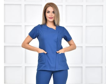 May include: A blue medical scrub top and pants set with a V-neck and short sleeves. The top has a diagonal seam and two pockets. The pants have a straight leg.