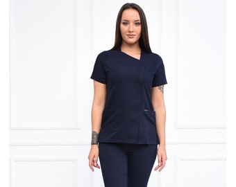 May include: A navy blue scrub top with a short sleeve and a diagonal zipper detail. The top has a pocket on the left side and a small logo on the right side.