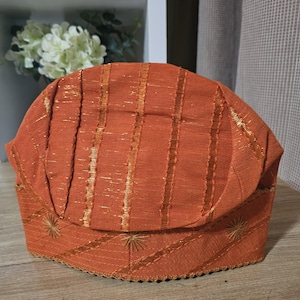 May include: A brown and gold striped fabric hat with a scalloped edge and embroidered stars.