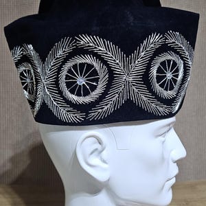 May include: A black velvet hat with a silver embroidered design. The hat has a wide brim and a rounded crown.